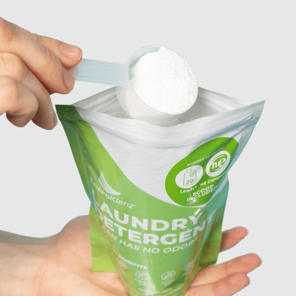 Hands Holding EnviroKlenz Laundry Detergent Powder With a Spoon Full of the Detergent Powder