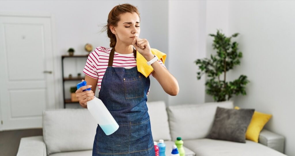 woman stifling sneeze while cleaning