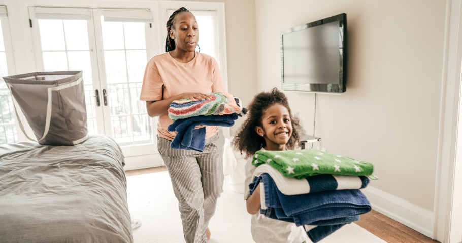 Mother and daughter walking and holding laundry