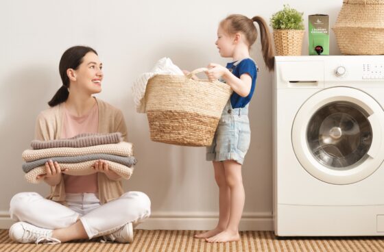 Mother and daughter at the washing machine with their laundry and the EnviroKlenz Liquid Laundry Enhancer