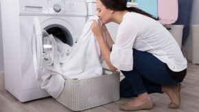 Woman smelling her fresh laundry with the EnviroKlenz Liquid Laundry Enhancer placed next to her